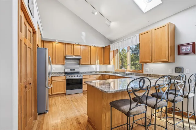 a kitchen with stainless steel appliances granite countertop sink stove refrigerator and cabinets