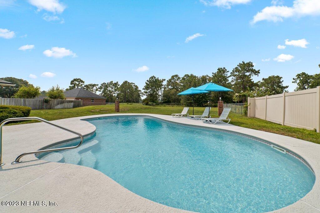 10079 Pebble Ridge Drive North Jacksonville, FL 32220 - Photo 27 of 32 a view of a swimming pool with an outdoor seating and a garden