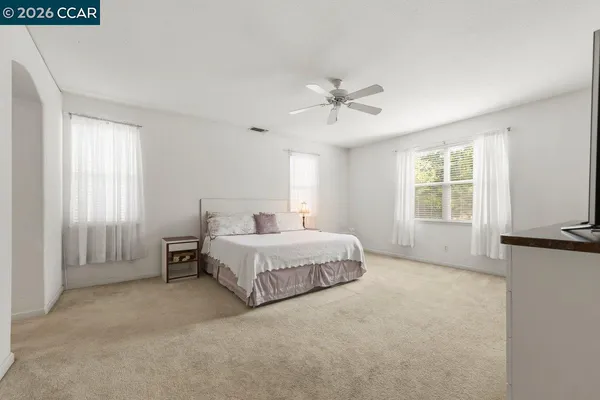 a spacious bedroom with a bed a chandelier and windows