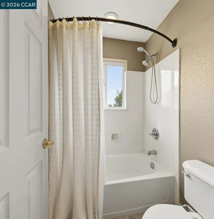 a bathroom with a shower curtain a toilet and a shower