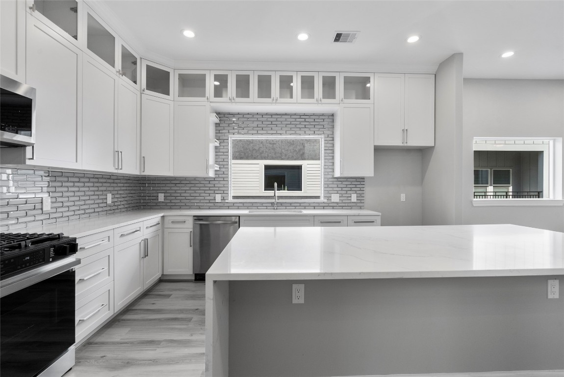 1122 West 16th Street, Unit B Houston, TX 77008 - Photo 14 of 31 a kitchen with kitchen island granite countertop a stove top oven a sink dishwasher and white cabinets