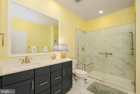 a bathroom with a double vanity sink toilet and shower