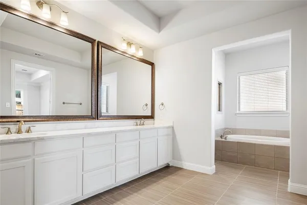 a bathroom with a double vanity sink and mirror with bathtub