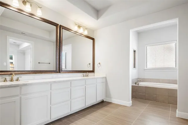 a bathroom with a double vanity sink and mirror with bathtub