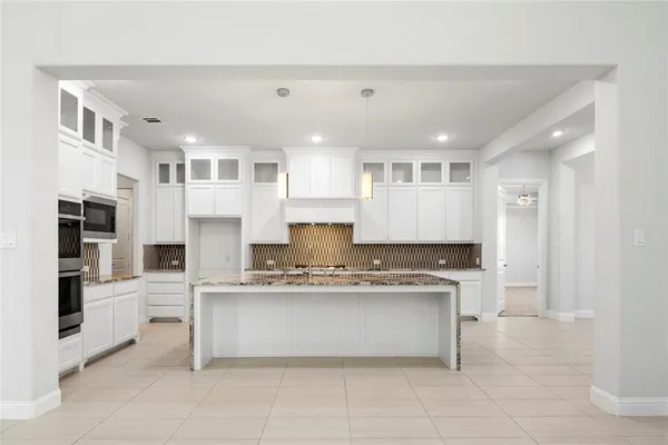 a large kitchen with stainless steel appliances granite countertop a stove and cabinets