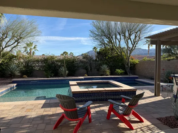 a view of swimming pool with chairs and wooden fence