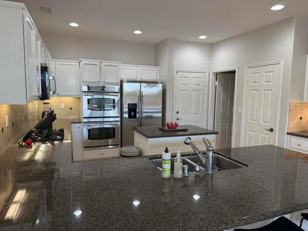 a kitchen with stainless steel appliances a dining table chairs stove and white cabinets