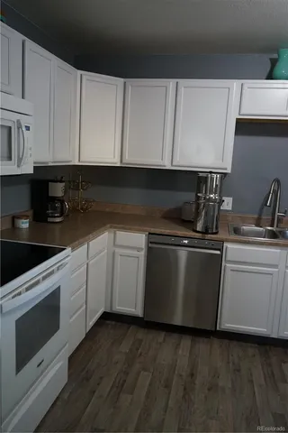 a kitchen with granite countertop white cabinets and white appliances