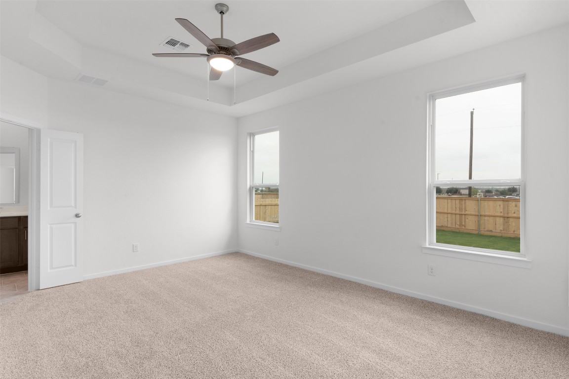 13821 Tucker Hedge Pass Elgin, TX 78621 - Photo 11 of 31 Spare room featuring a tray ceiling, light carpet, and ceiling fan