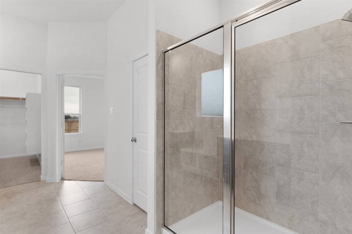 13821 Tucker Hedge Pass Elgin, TX 78621 - Photo 13 of 31 Full bathroom featuring a stall shower, light tile patterned floors, a spacious closet, and light colored carpet
