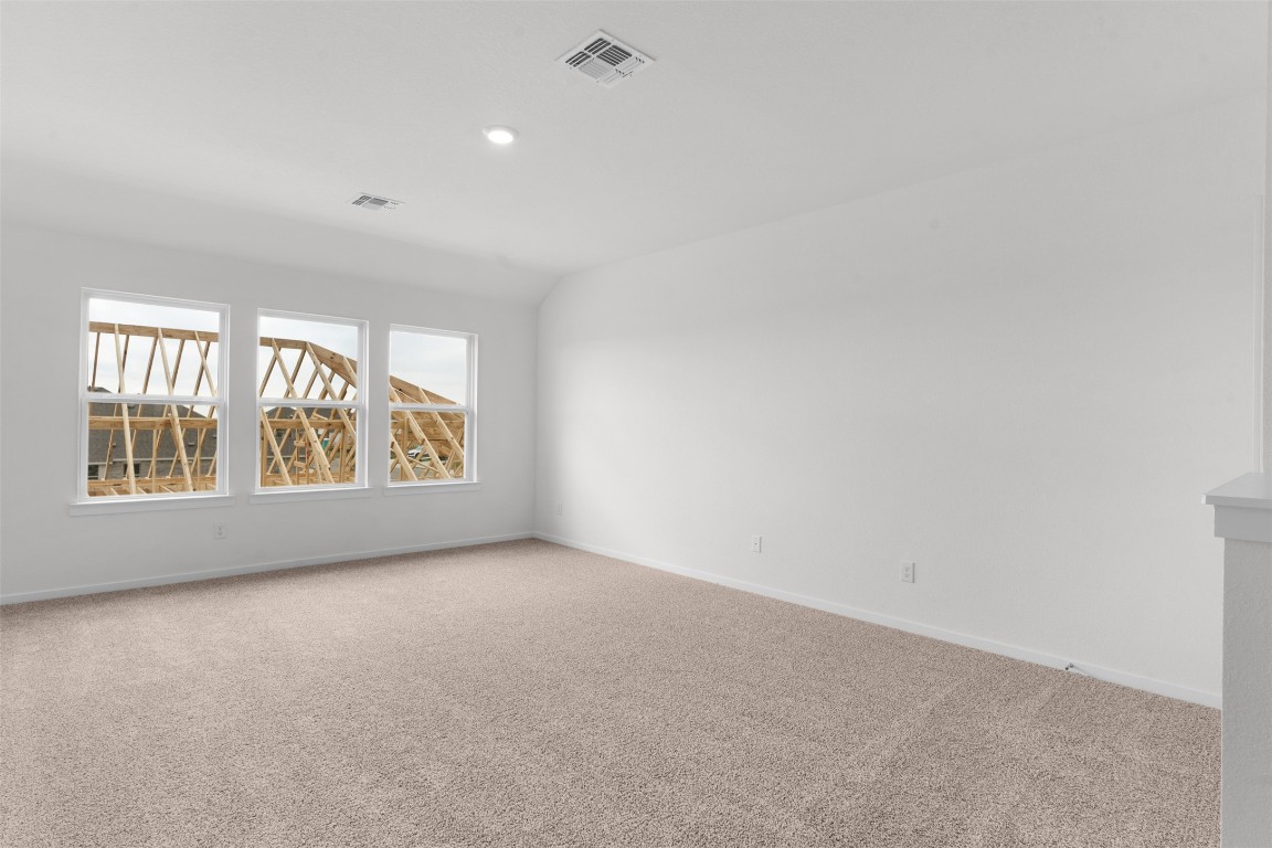 13821 Tucker Hedge Pass Elgin, TX 78621 - Photo 16 of 31 Unfurnished room with light carpet and vaulted ceiling