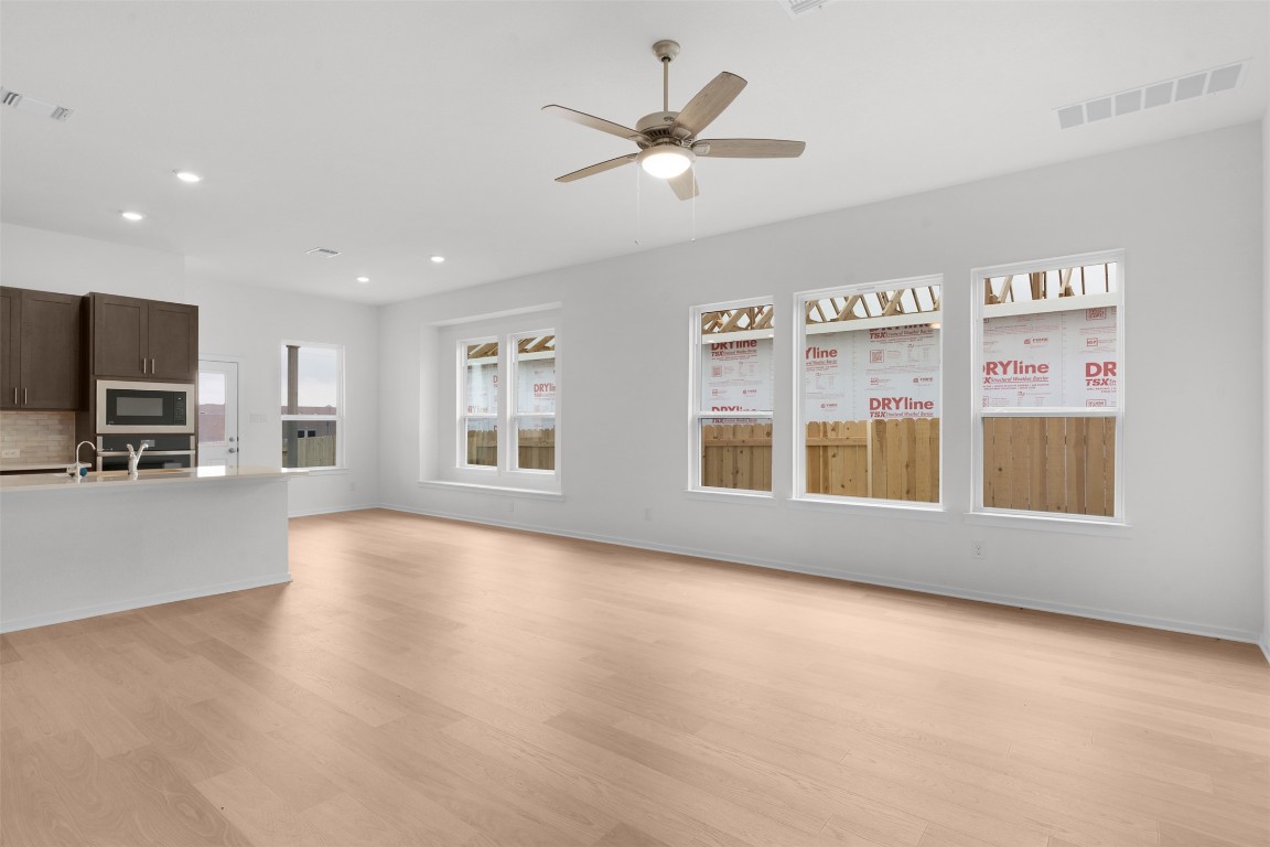 13821 Tucker Hedge Pass Elgin, TX 78621 - Photo 6 of 31 Unfurnished living room featuring light wood-style floors, a ceiling fan, and recessed lighting