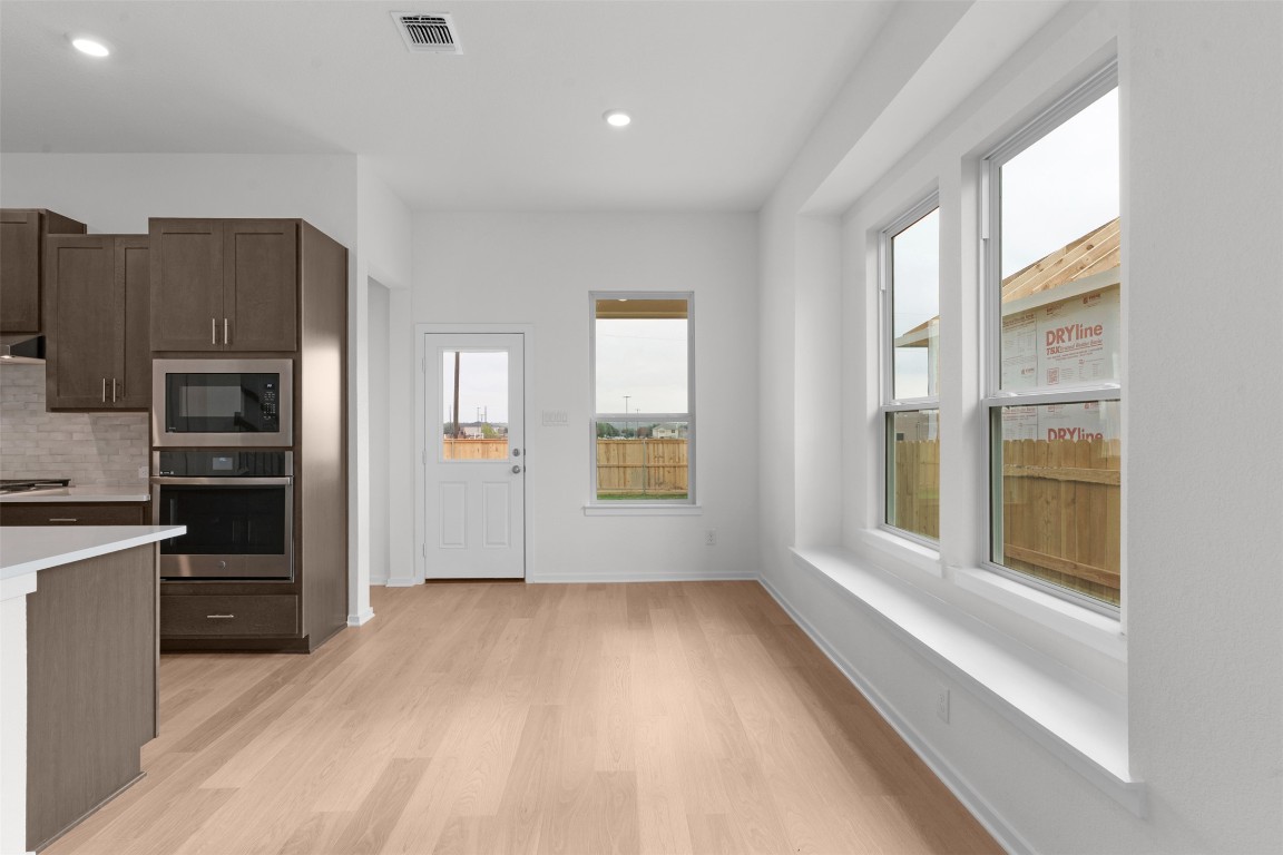 13821 Tucker Hedge Pass Elgin, TX 78621 - Photo 10 of 31 Kitchen with stainless steel appliances, tasteful backsplash, dark brown cabinetry, light wood-style floors, and recessed lighting