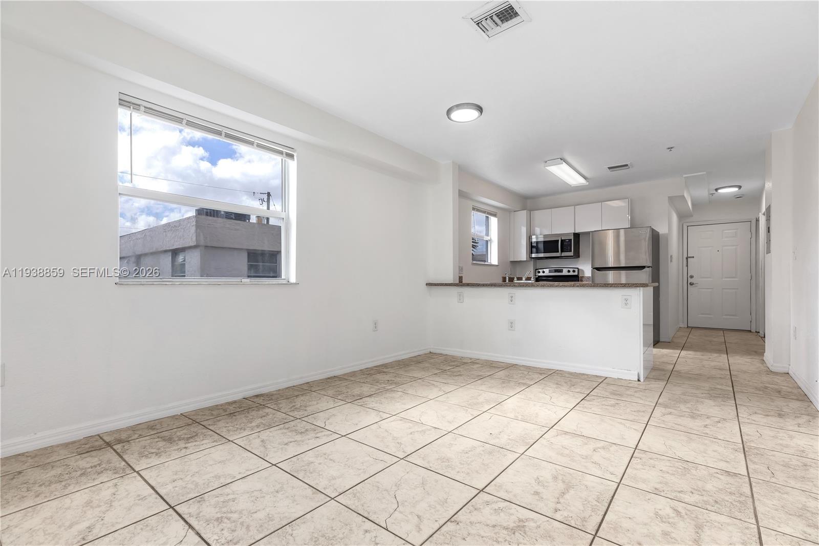 520 Southwest 5th Street, Unit 303 Miami, FL 33130 - Photo 10 of 20 a kitchen with stainless steel appliances kitchen island granite countertop white cabinets and window