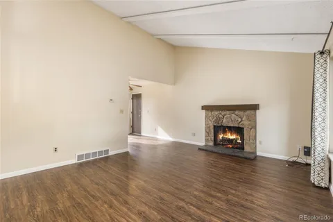 an empty room with wooden floor fire place and windows