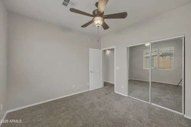 an empty room with ceiling fan and window
