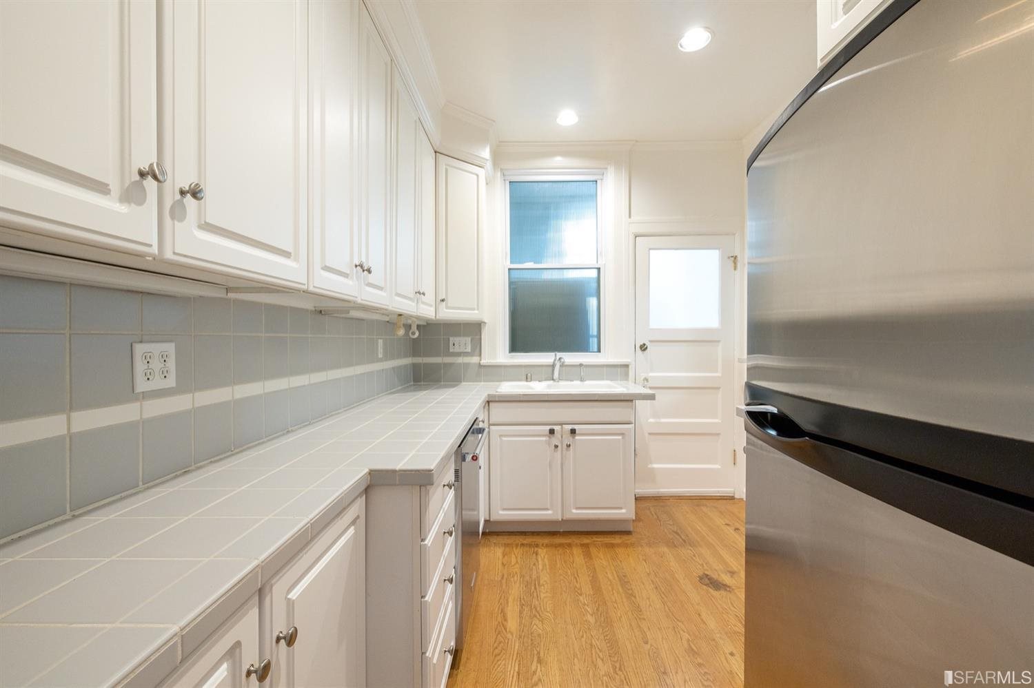 1069 Broadway San Francisco, CA 94133 - Photo 24 of 43 a kitchen with a sink dishwasher and a stove top oven with wooden floor