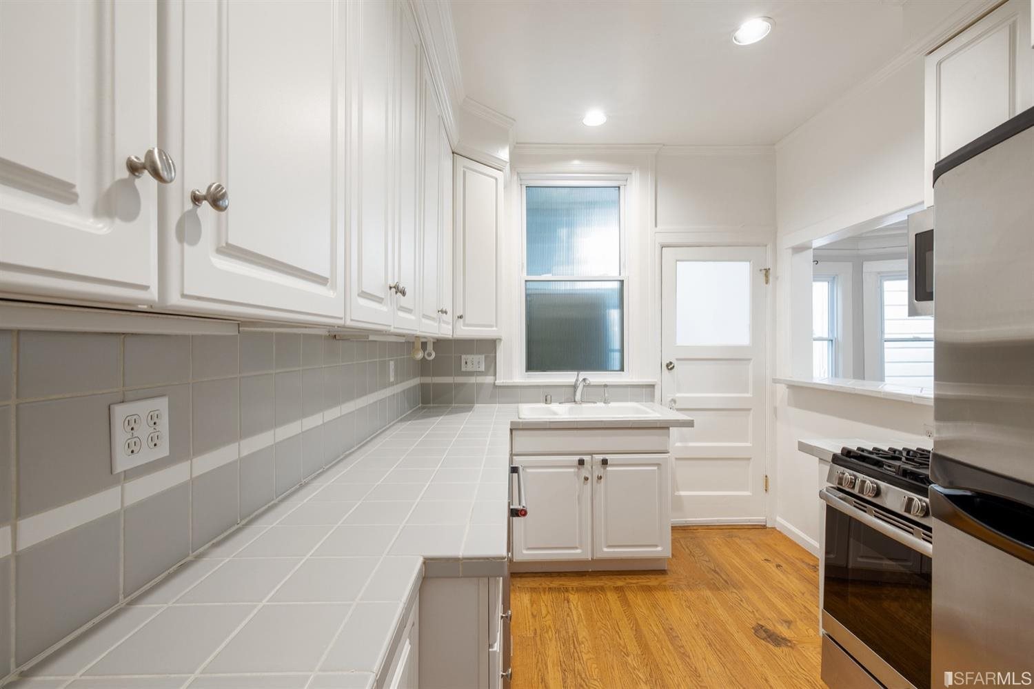 1069 Broadway San Francisco, CA 94133 - Photo 3 of 43 a kitchen with stainless steel appliances white cabinets and wooden floor