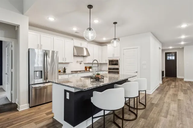 a kitchen with stainless steel appliances granite countertop a sink a stove a refrigerator cabinets and chairs