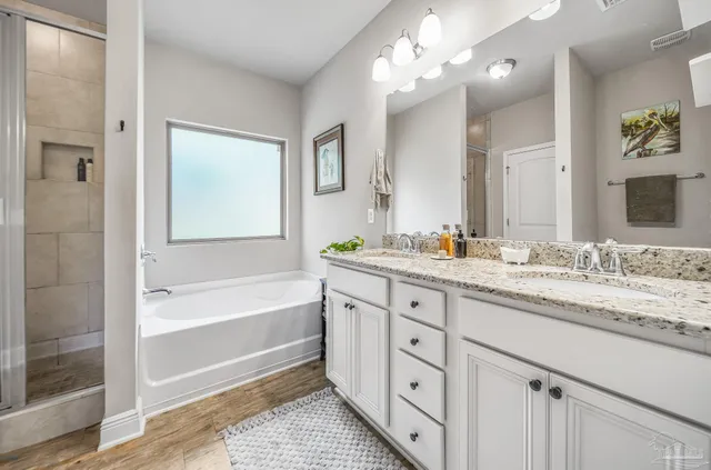 a bathroom with a granite countertop double vanity sink a mirror and a bathtub