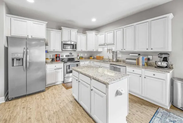 a kitchen with white cabinets sink and refrigerator