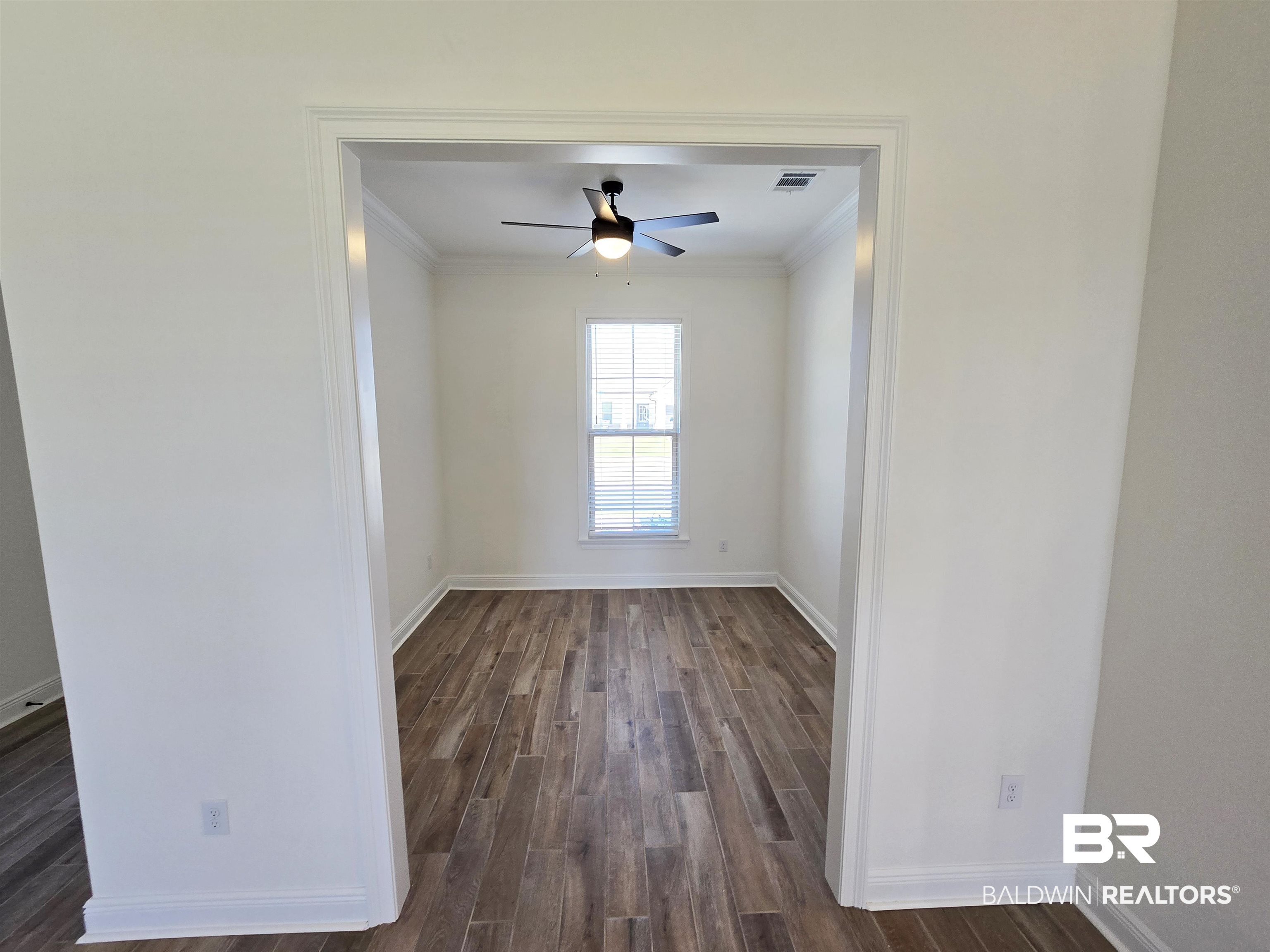 11178 Bonaventure Avenue Daphne, AL 36526 - Photo 7 of 20 Empty room with dark wood-style flooring, ornamental molding, and ceiling fan
