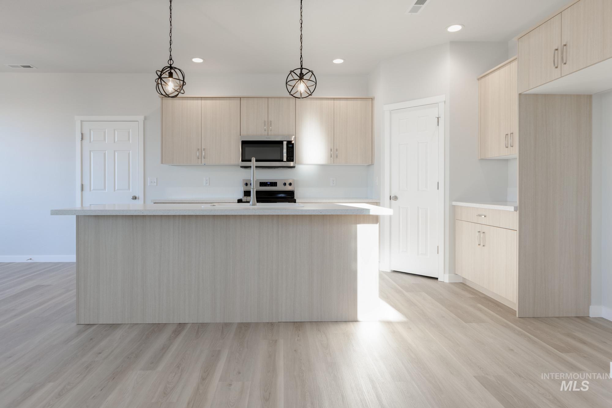 1639 Celina Street Middleton, ID 83644 - Photo 2 of 19 Kitchen with light wood-finish cabinetry, a large center island with integrated sink, and stainless steel appliances