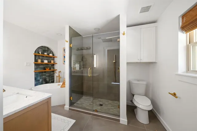 a bathroom with a shower sink mirror and toilet