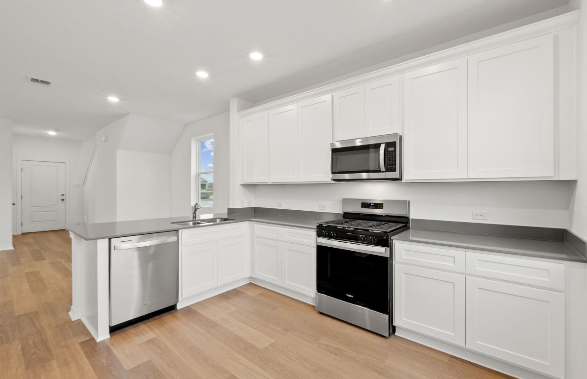 333 Sullivan Way Elgin, TX 78621 - Photo 3 of 18 a kitchen with stainless steel appliances granite countertop a stove a sink and white cabinets