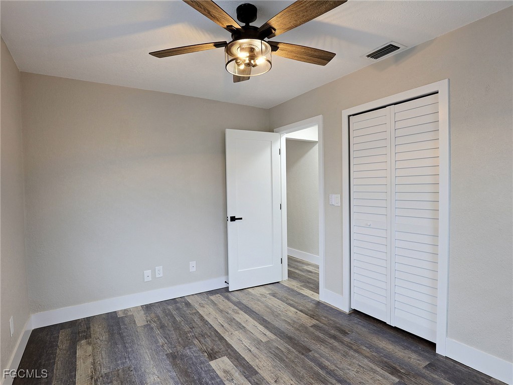 14181 Old Olga Road Fort Myers, FL 33905 - Photo 8 of 13 a view of an empty room with chandelier fan and wooden floor