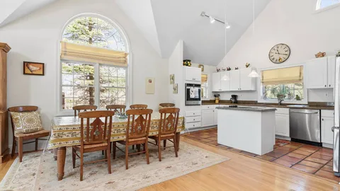 a dining room with kitchen island wooden floor and a large window