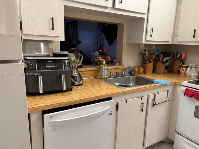 a kitchen with a stove a sink and a white cabinets