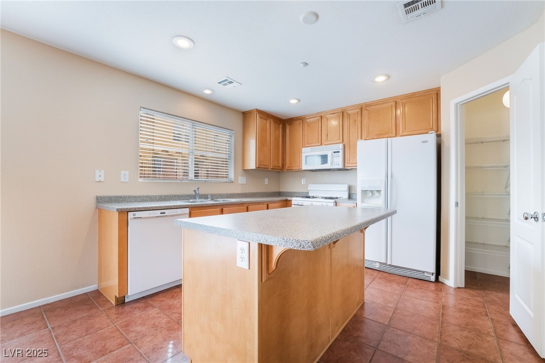 1152 Gecko Road Henderson, NV 89002 - Photo 9 of 32 Kitchen featuring white appliances, a kitchen island, visible vents, and a sink
