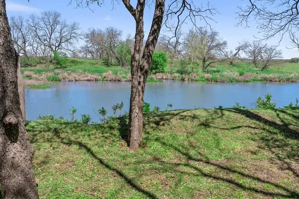 a view of a lake with a big yard and large trees