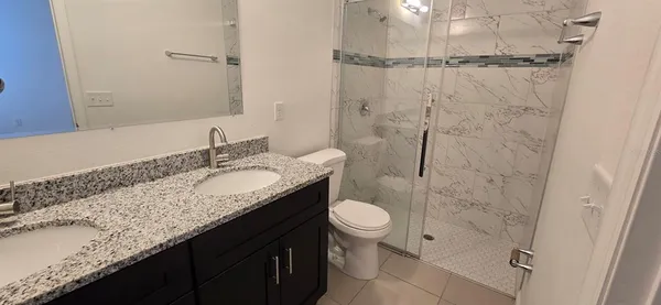 a bathroom with a granite countertop sink toilet and shower