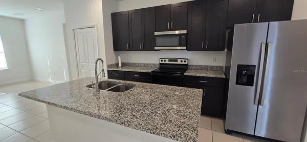 a kitchen with stainless steel appliances granite countertop a refrigerator a stove and a sink with wooden floor