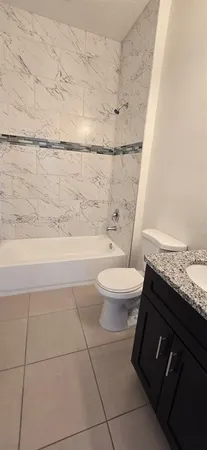 a bathroom with a granite countertop bathtub toilet and sink