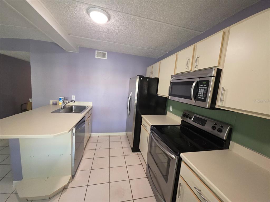 1601 Big Tree Road, Unit 901 Daytona Beach, FL 32119 - Photo 7 of 68 a kitchen with stainless steel appliances a sink a stove a refrigerator a microwave a sink and white cabinets