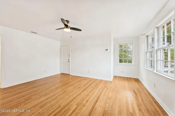 a view of empty room with wooden floor and fan