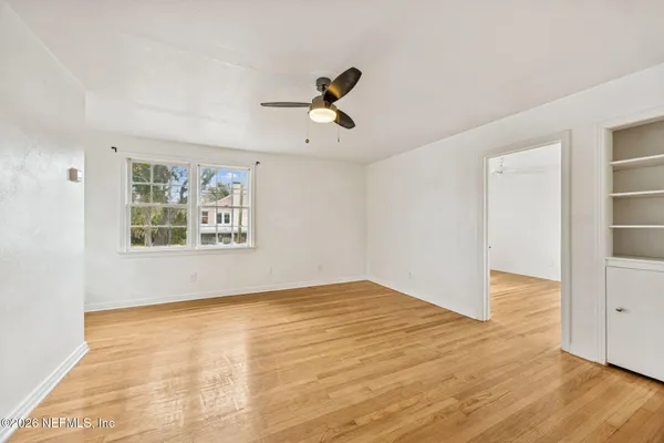 a view of empty room with wooden floor and fan