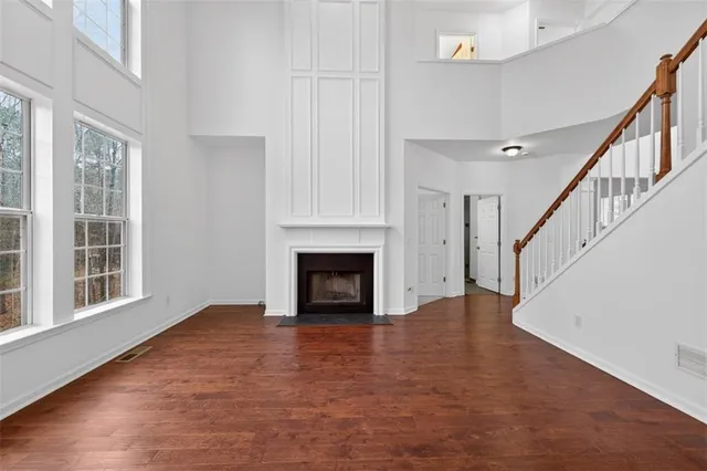 a view of an empty room with wooden floor fireplace and a window