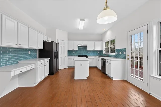 a kitchen with a refrigerator a stove top oven a sink dishwasher and white cabinets with wooden floor