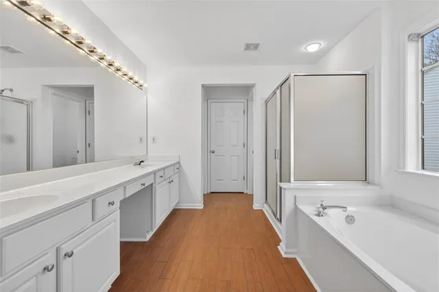 a spacious bathroom with a double vanity sink a large mirror and a bathtub