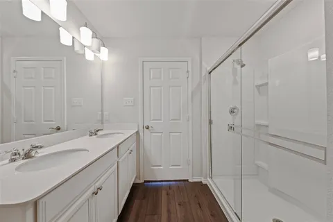 a bathroom with a double vanity sink a large mirror and shower
