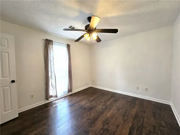 an empty room with wooden floor ceiling fan and window