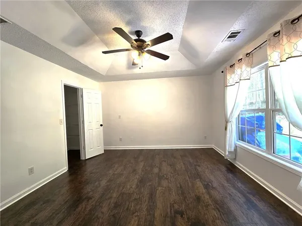 an empty room with wooden floor fan and windows