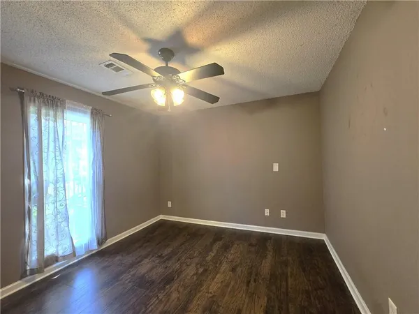 an empty room with wooden floor and windows