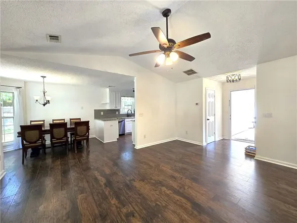 a view of a dining room and livingroom with furniture wooden floor a chandelier