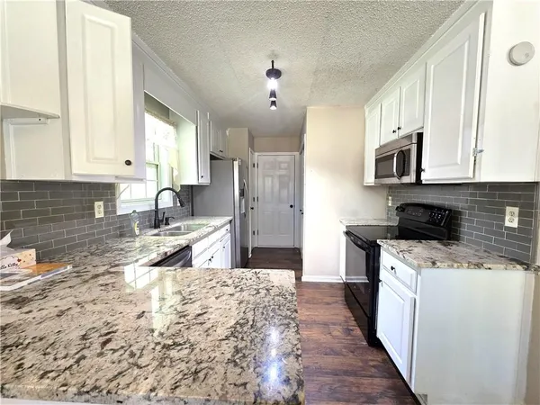 a kitchen with stainless steel appliances granite countertop a stove a sink and a refrigerator