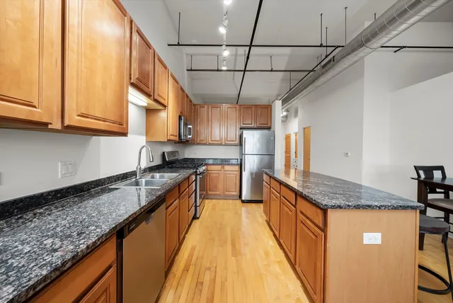 a kitchen with stainless steel appliances granite countertop a sink a stove and cabinets